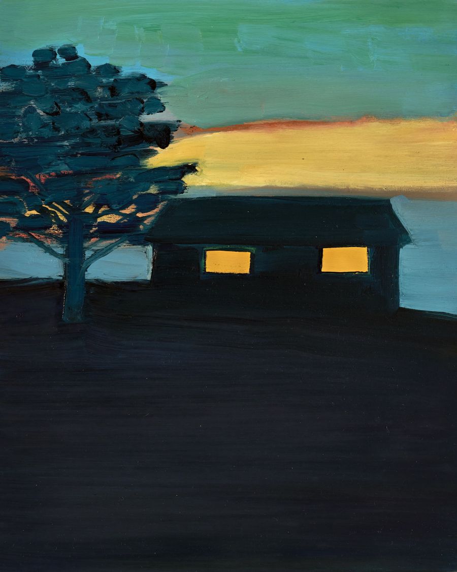 A dark shack at dusk with lit-up windows and a tree standing next to it.