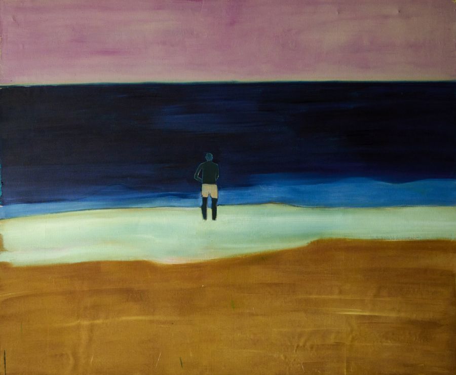 A male figure standing and looking out over the seashore..