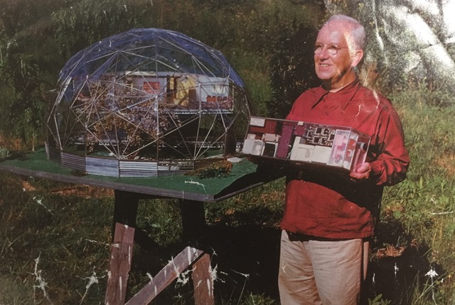 A picture of a Buckminster Fuller holding a house model.