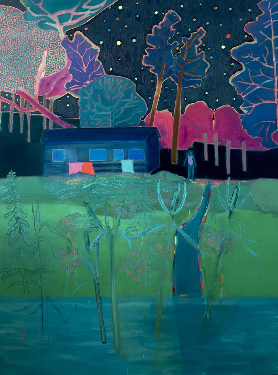 A swimmer standing outside a house at night, in front of colourful trees.